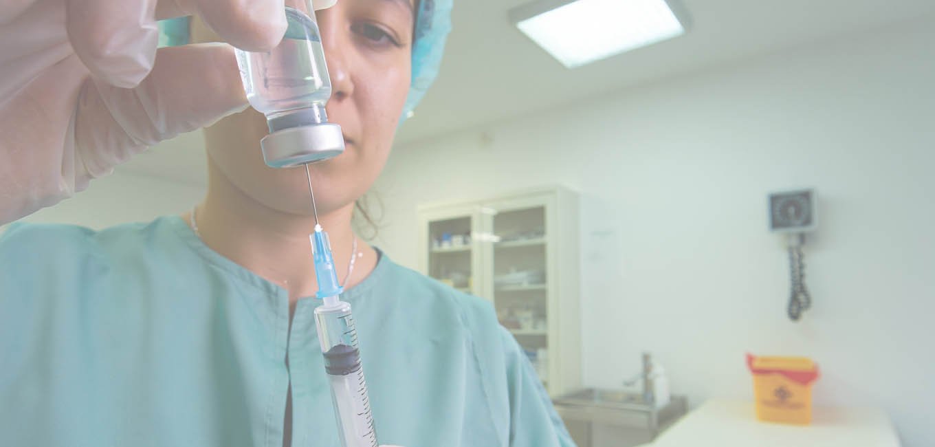 Медик в перчатках заполняет шприц препаратом